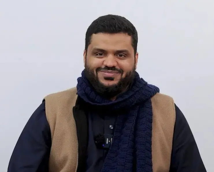 أحمد السيد مبتسمًا بوشاحٍ كحليّ