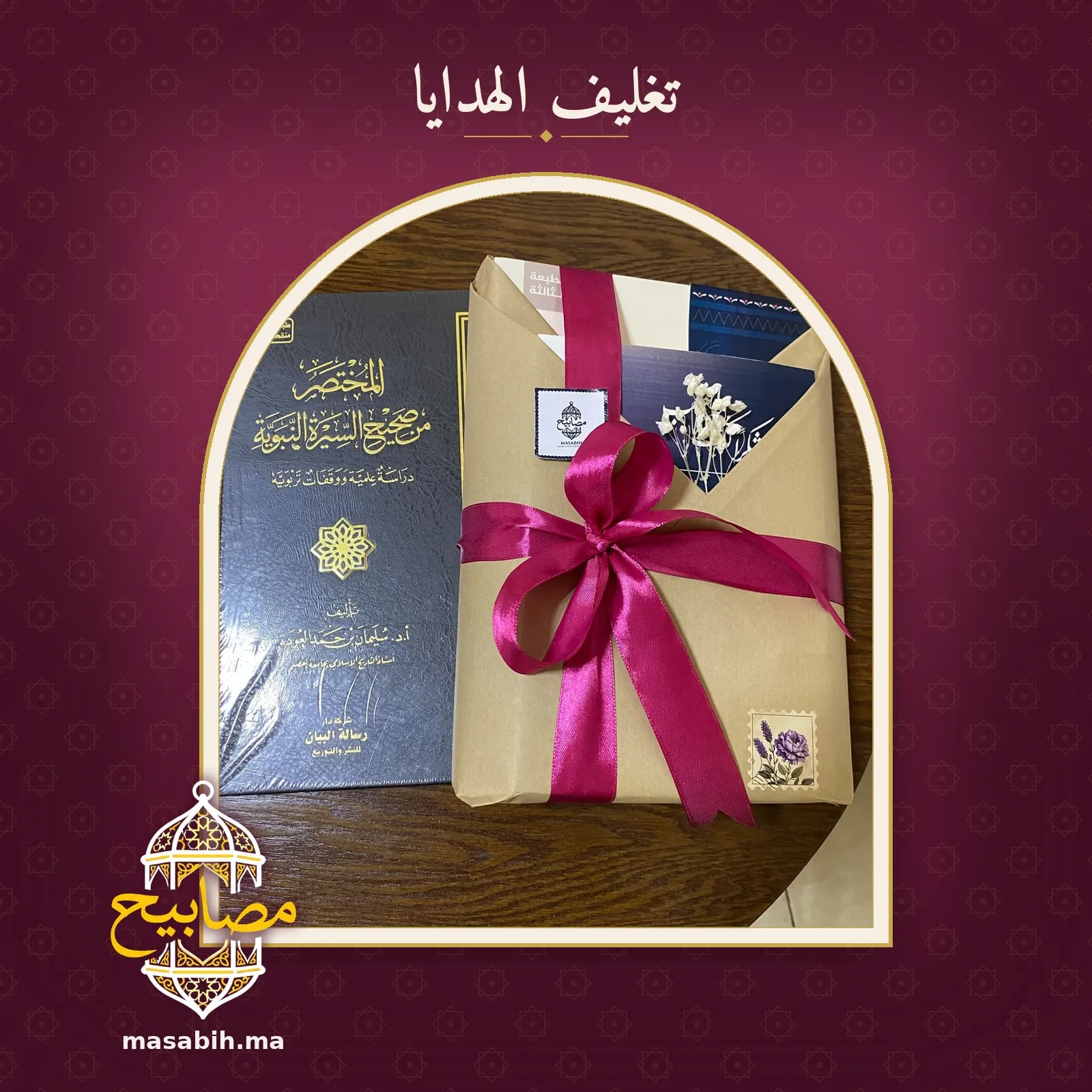 الهدية مشدودةٌ بشريطٍ وردي معقود، بجانب كتابٍ مجلّدٍ بغلافٍ أسود مذهّب